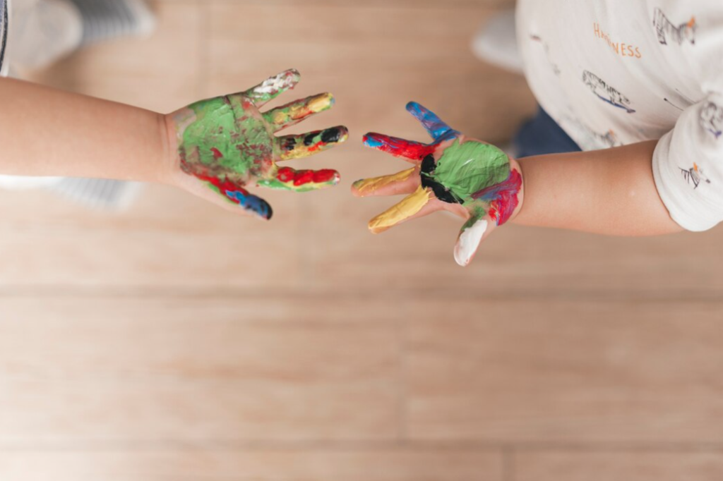 Children's hands covered in colorful paint, symbolizing the freedom of expression and the joys of art.
